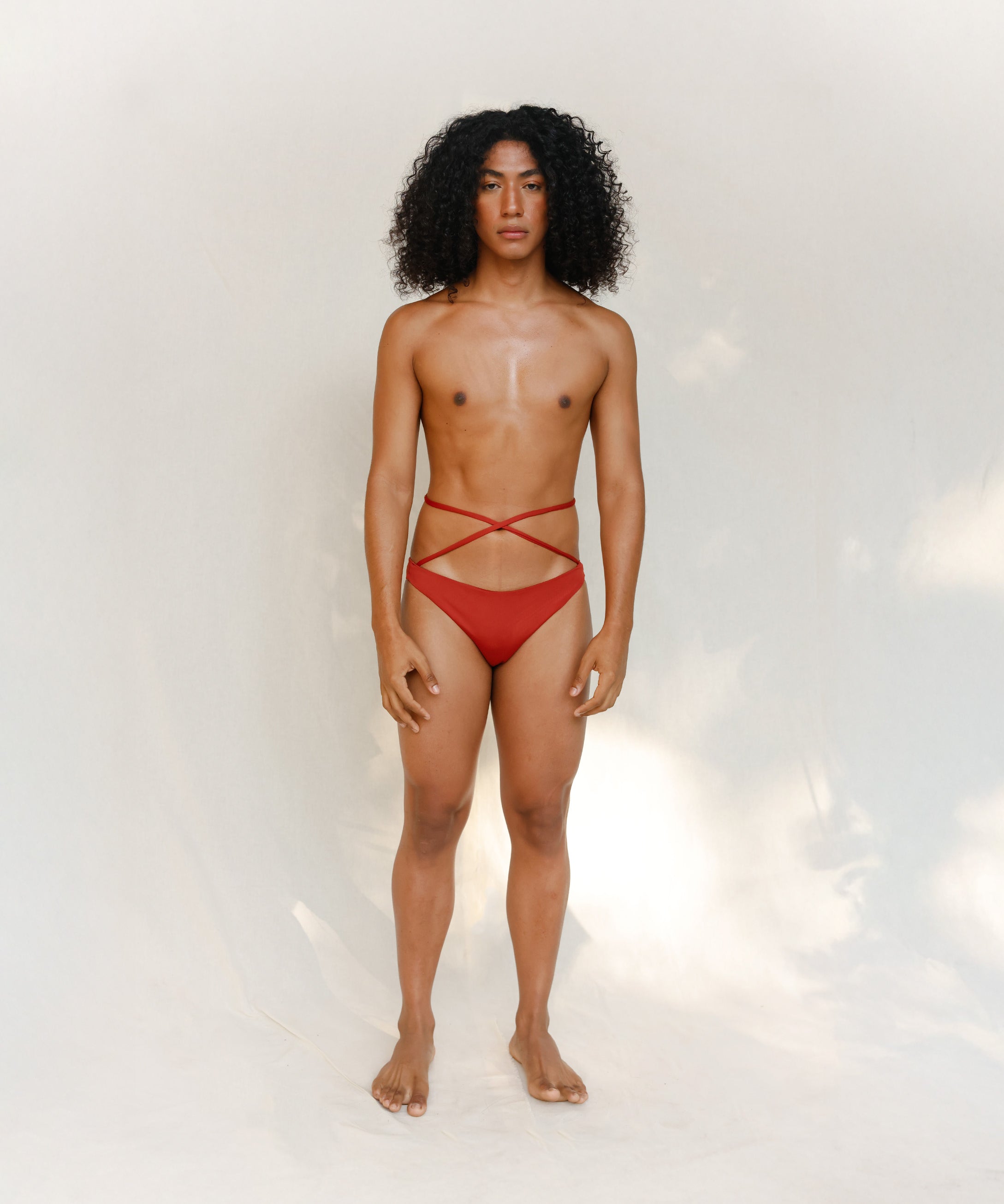 This bikini bottom is a gender-neutral, nonbinary Venus eco striped design in terracotta red, shown from the front. 