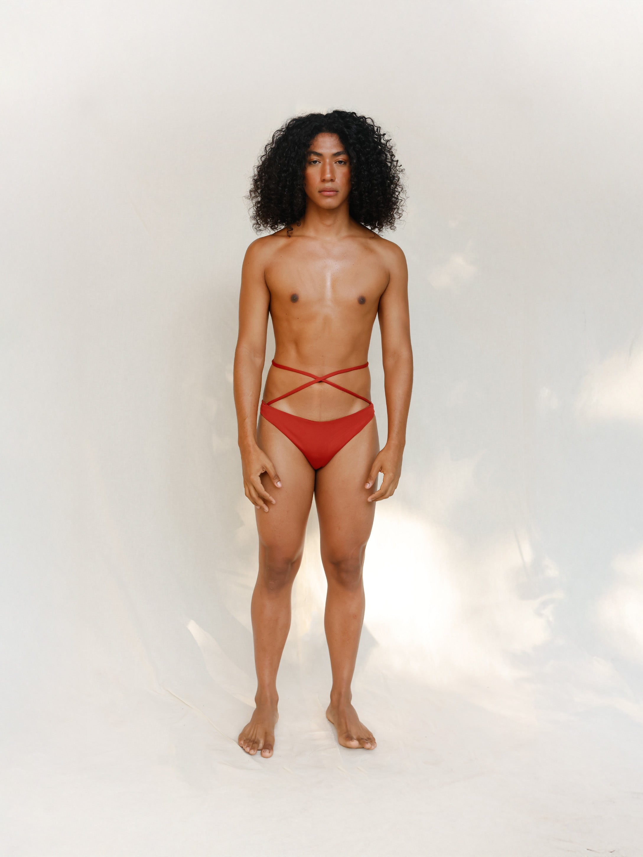 This bikini bottom is a gender-neutral, nonbinary Venus eco striped design in terracotta red, shown from the front. 