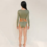 this picture is showcasing back view of the Doris long-sleeve swim crop top rashguard in mineral green paired paired with the Venus striped bikini bottom.it's a gender-neutral, nonbinary sustainable swimwear set with a clean, modern silhouette.