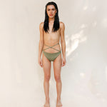 Model is wearing the Venus eco striped bikini bottom in mineral green which is a gender-neutral, nonbinary sustainable design shown from the front. it has a clean, minimal fit.