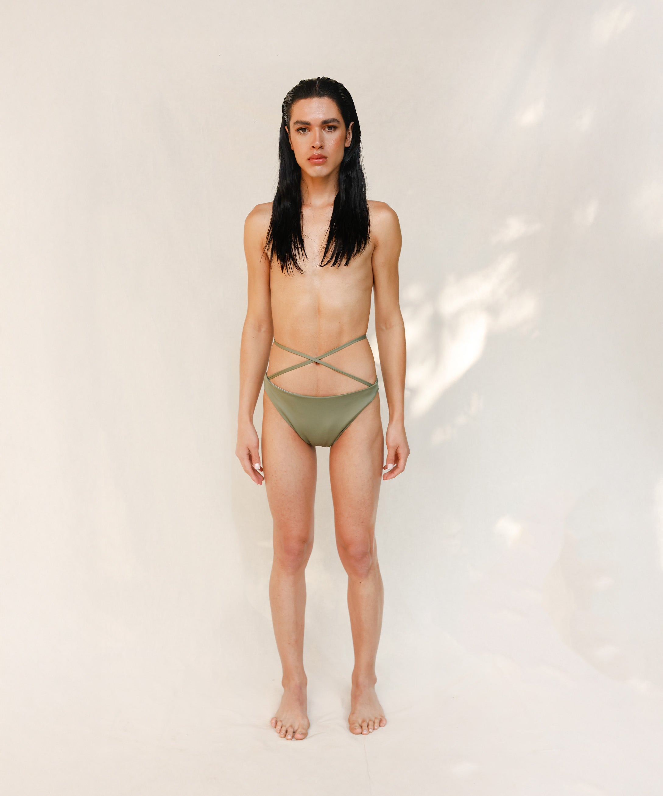 Model is wearing the Venus eco striped bikini bottom in mineral green which is a gender-neutral, nonbinary sustainable design shown from the front. it has a clean, minimal fit.
