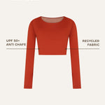 Front close-up showing the sustainable details of a terracotta red long-sleeve rashguard, designed as gender-neutral, nonbinary skin-wear with a sleek and minimal finish.