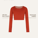 Front close-up showing the sustainable details of a terracotta red long-sleeve rashguard, designed as gender-neutral, nonbinary skin-wear with a sleek and minimal finish.