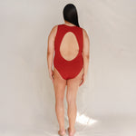 Person wearing Marsha one-piece swimsuit in terracotta red, back view