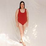 Person wearing Marsha one-piece swimsuit in terracotta red, front view