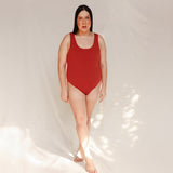 Person wearing Marsha one-piece swimsuit in terracotta red, front view