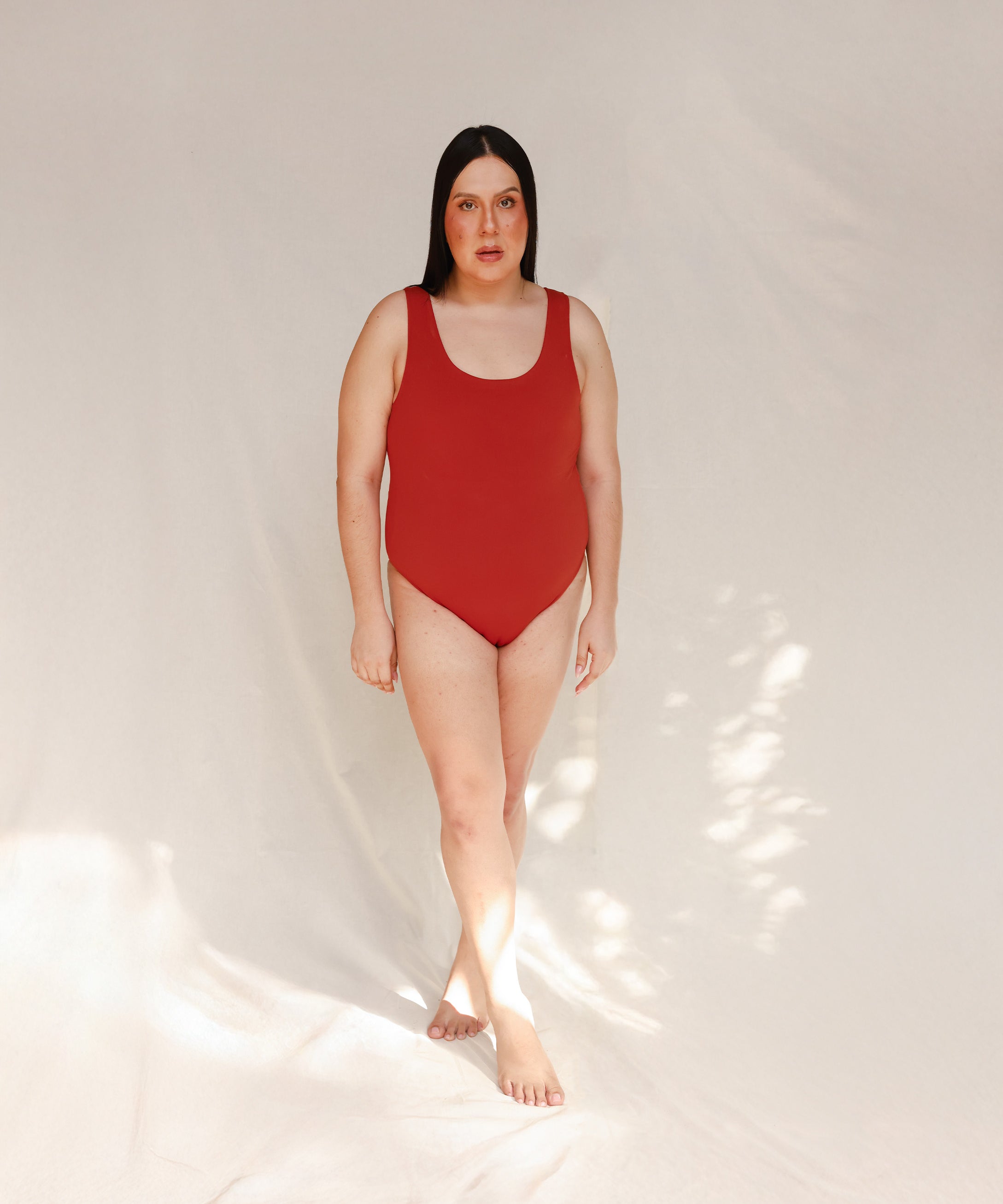 Person wearing Marsha one-piece swimsuit in terracotta red, front view