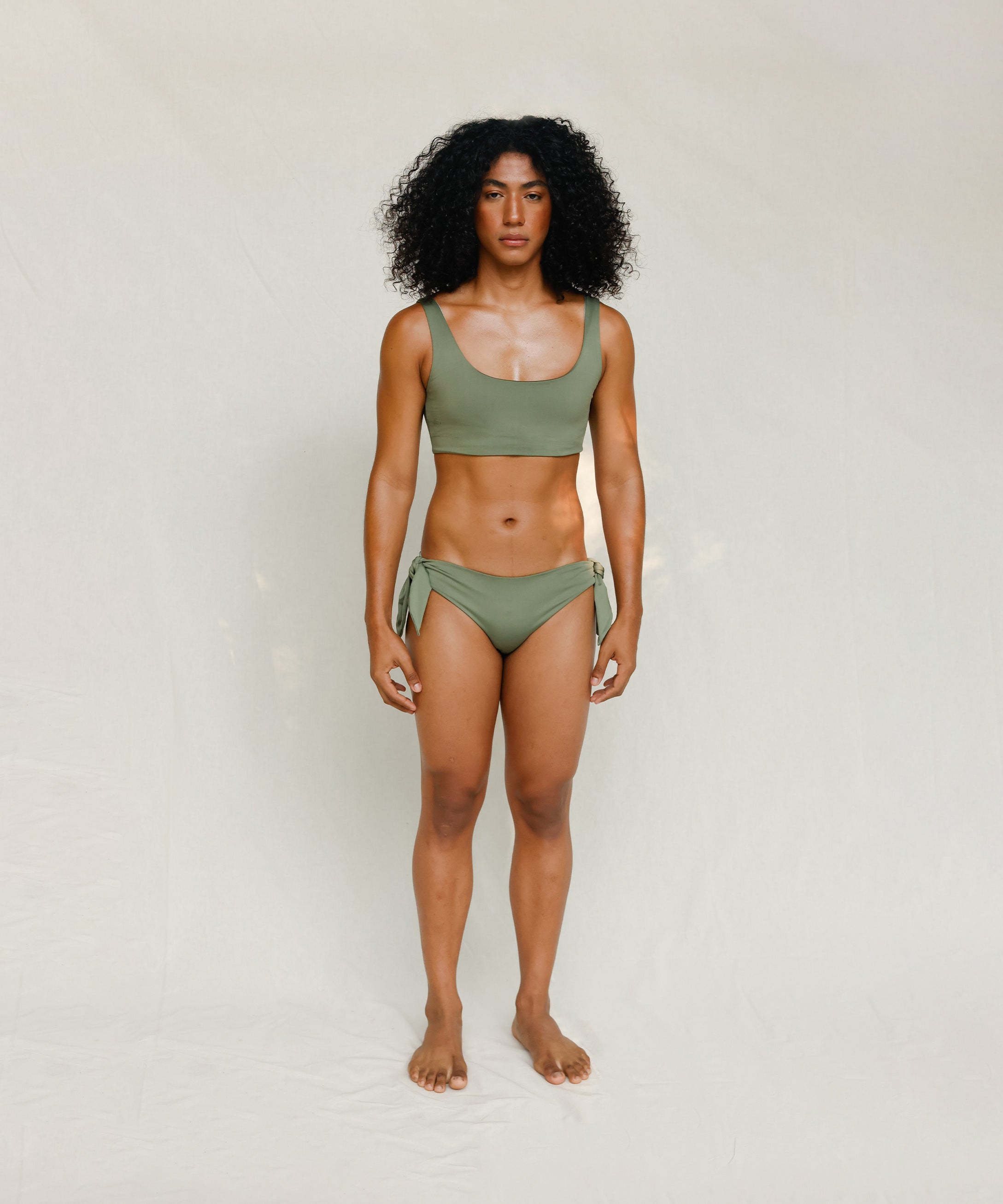 Front view of model wearing green swim top with scoop neck. 