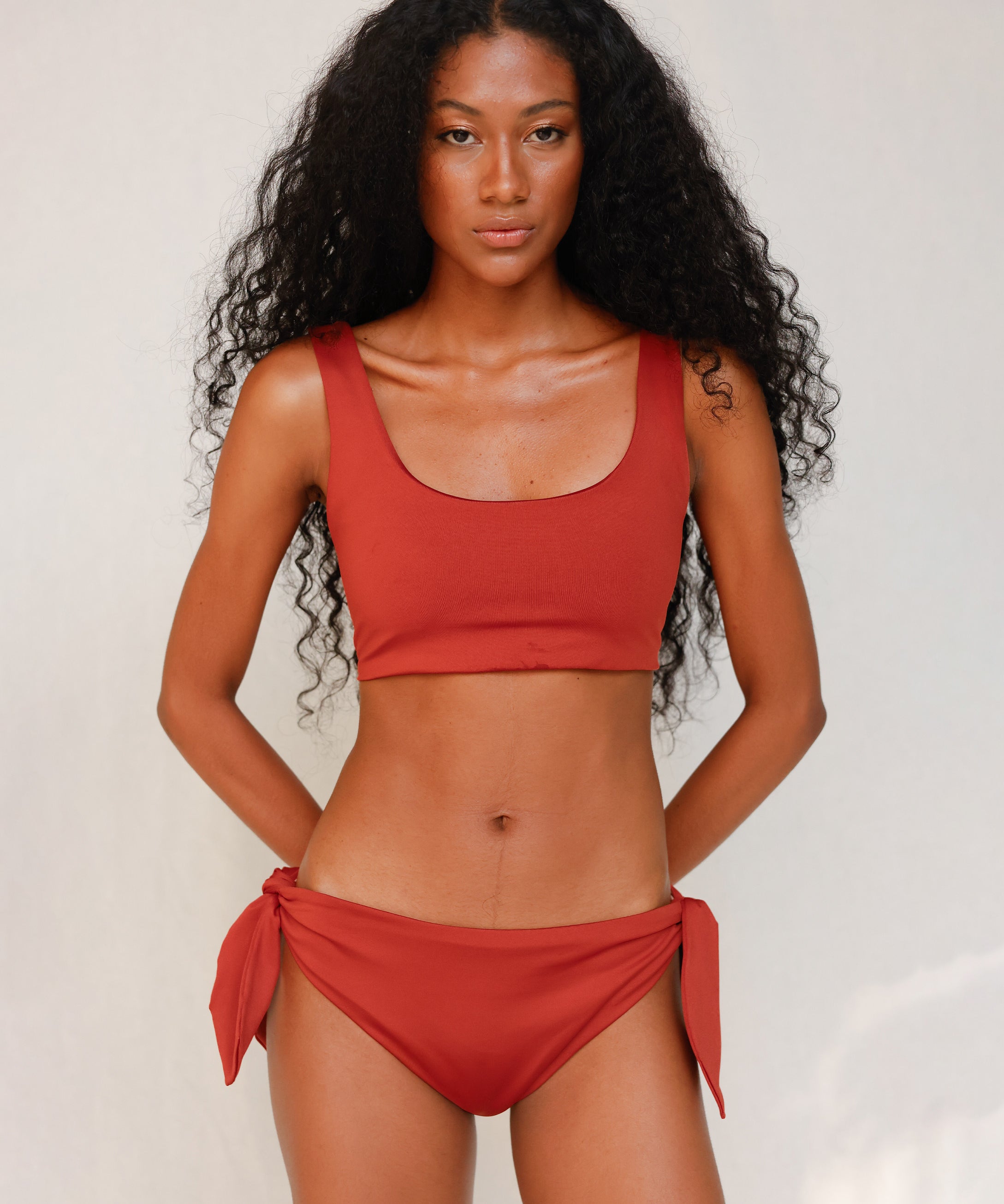 Front view of model wearing red swim top with scoop neck