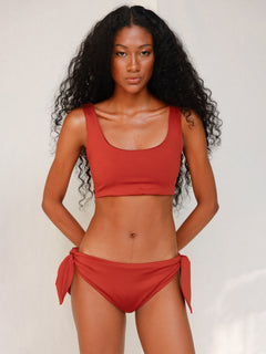 Front view of model wearing red swim top with scoop neck
