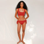 Front view of model wearing red swim top with scoop neck 