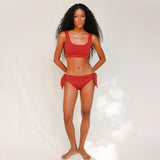 Front view of model wearing red swim top with scoop neck 