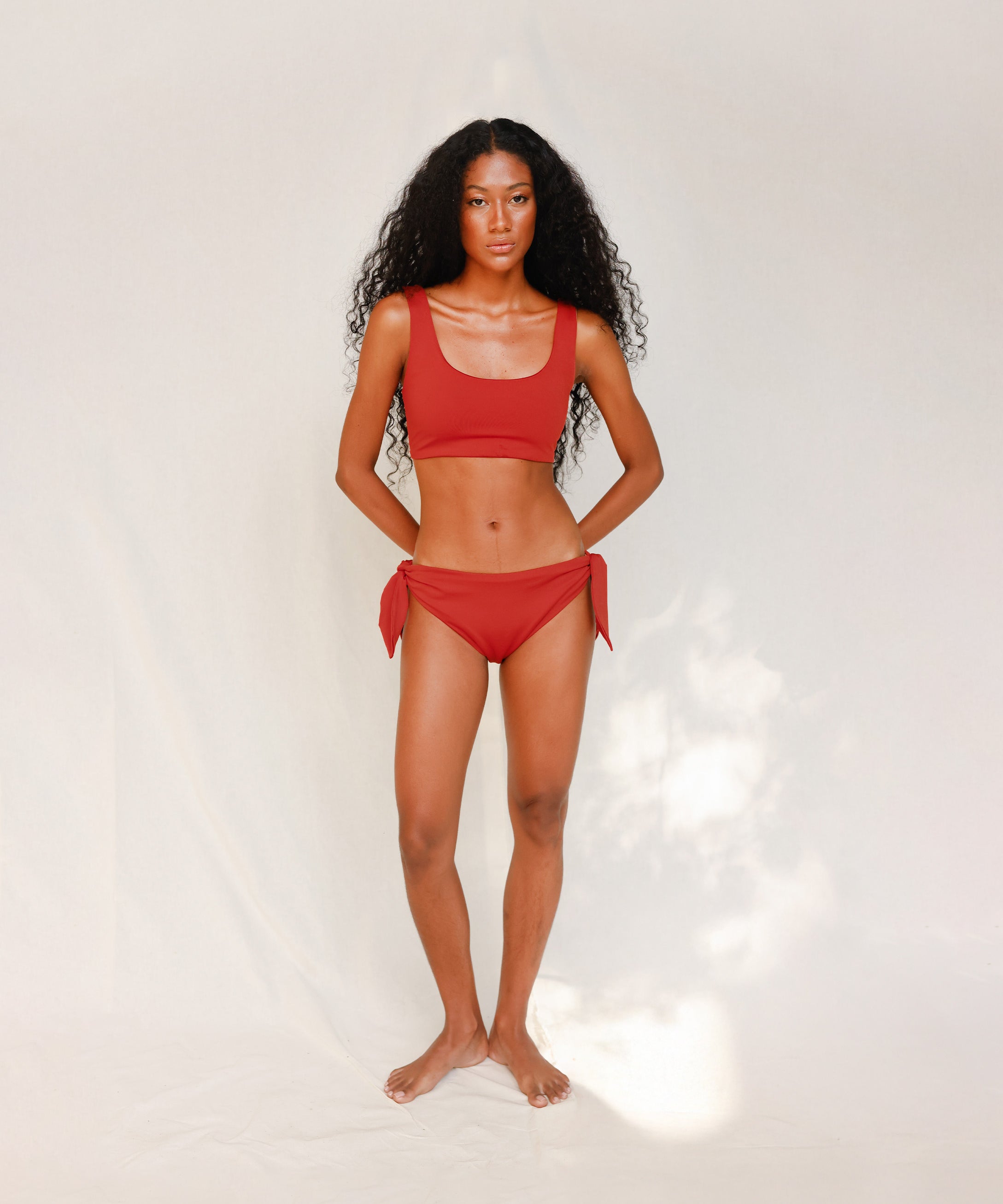 Front view of model wearing red swim top with scoop neck 