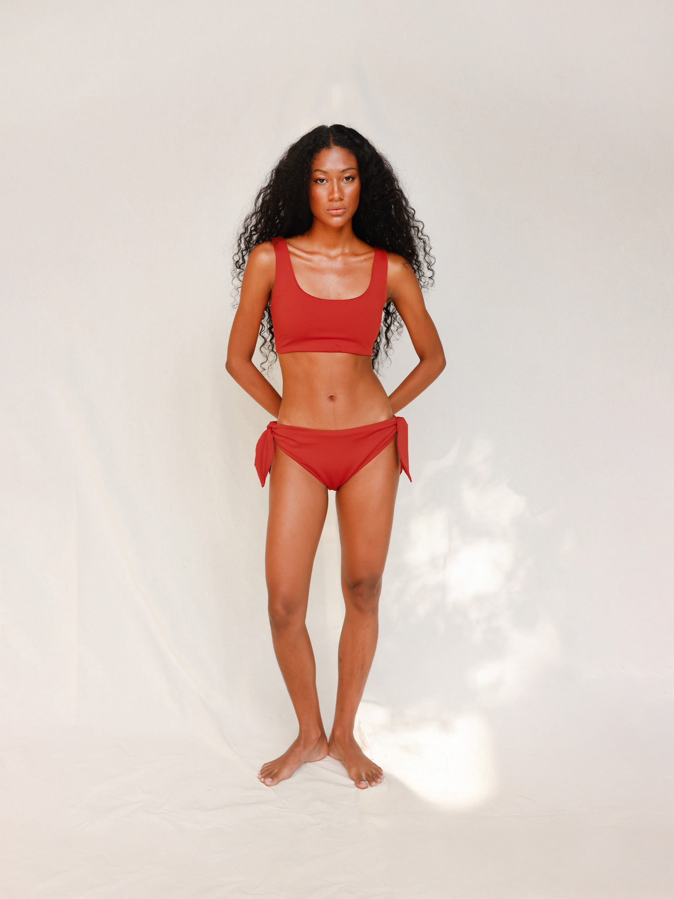 Front view of model wearing red swim top with scoop neck 