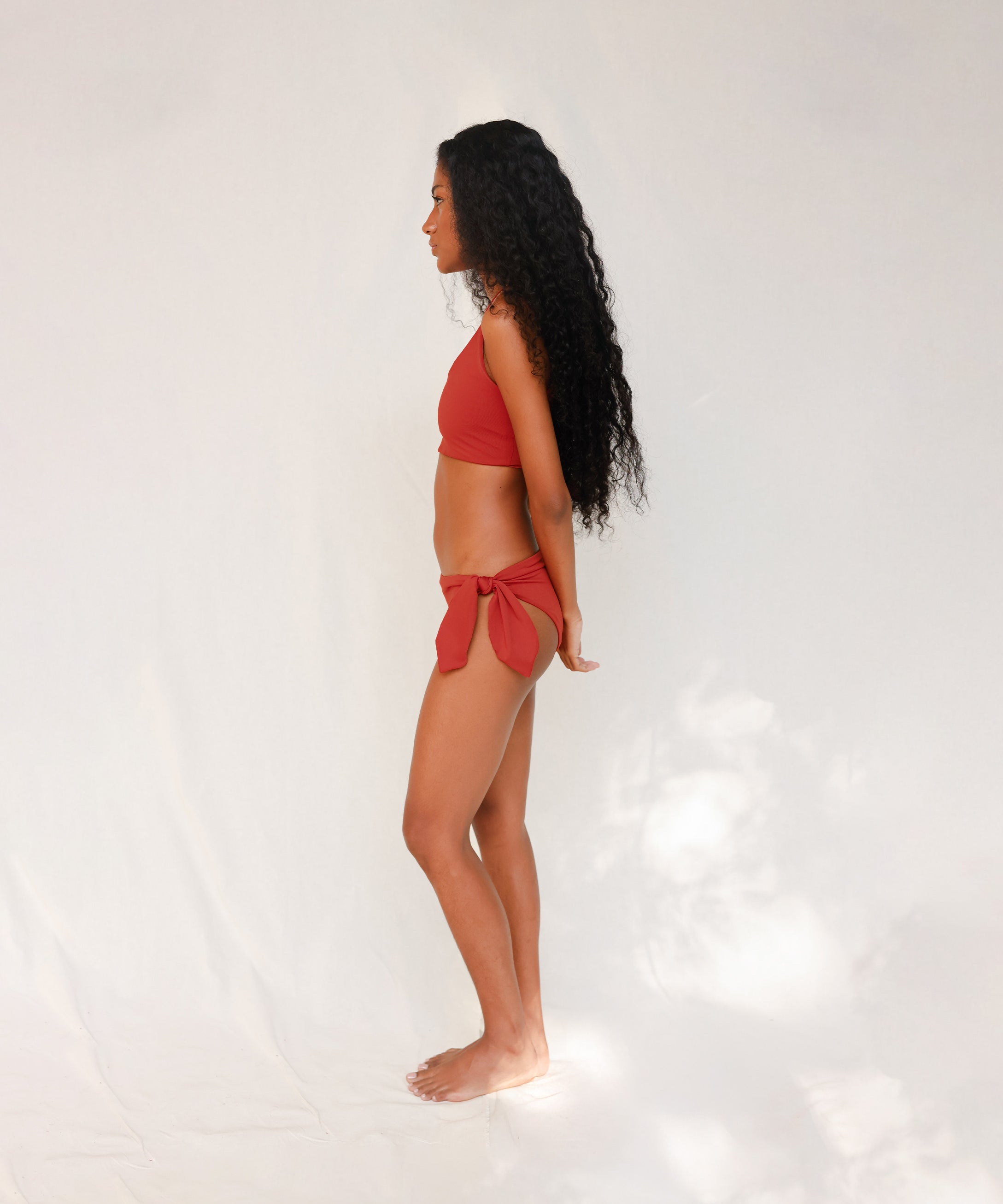 Side view of model in Audre top, terracotta red 