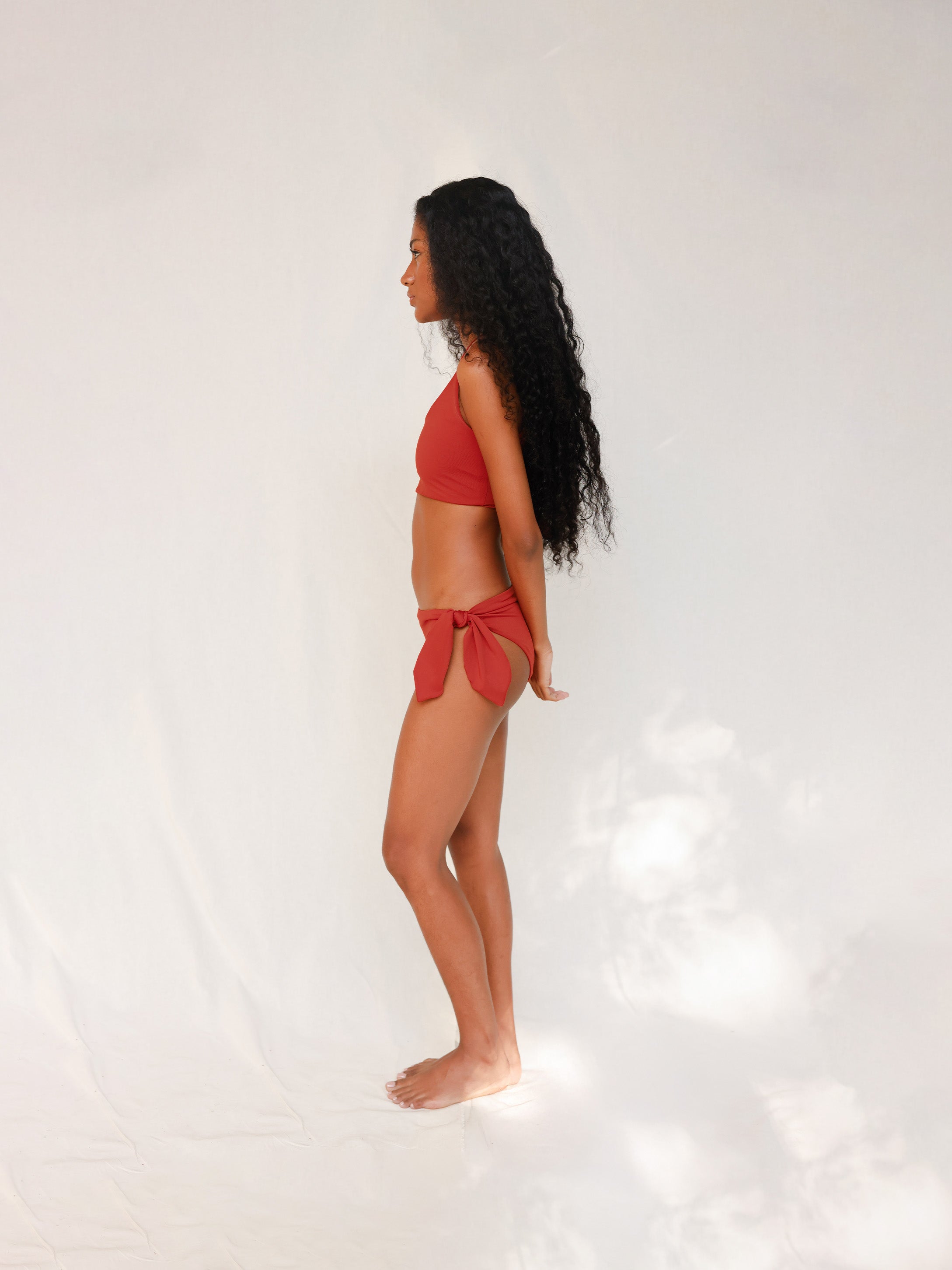 Side view of model in Audre top, terracotta red 