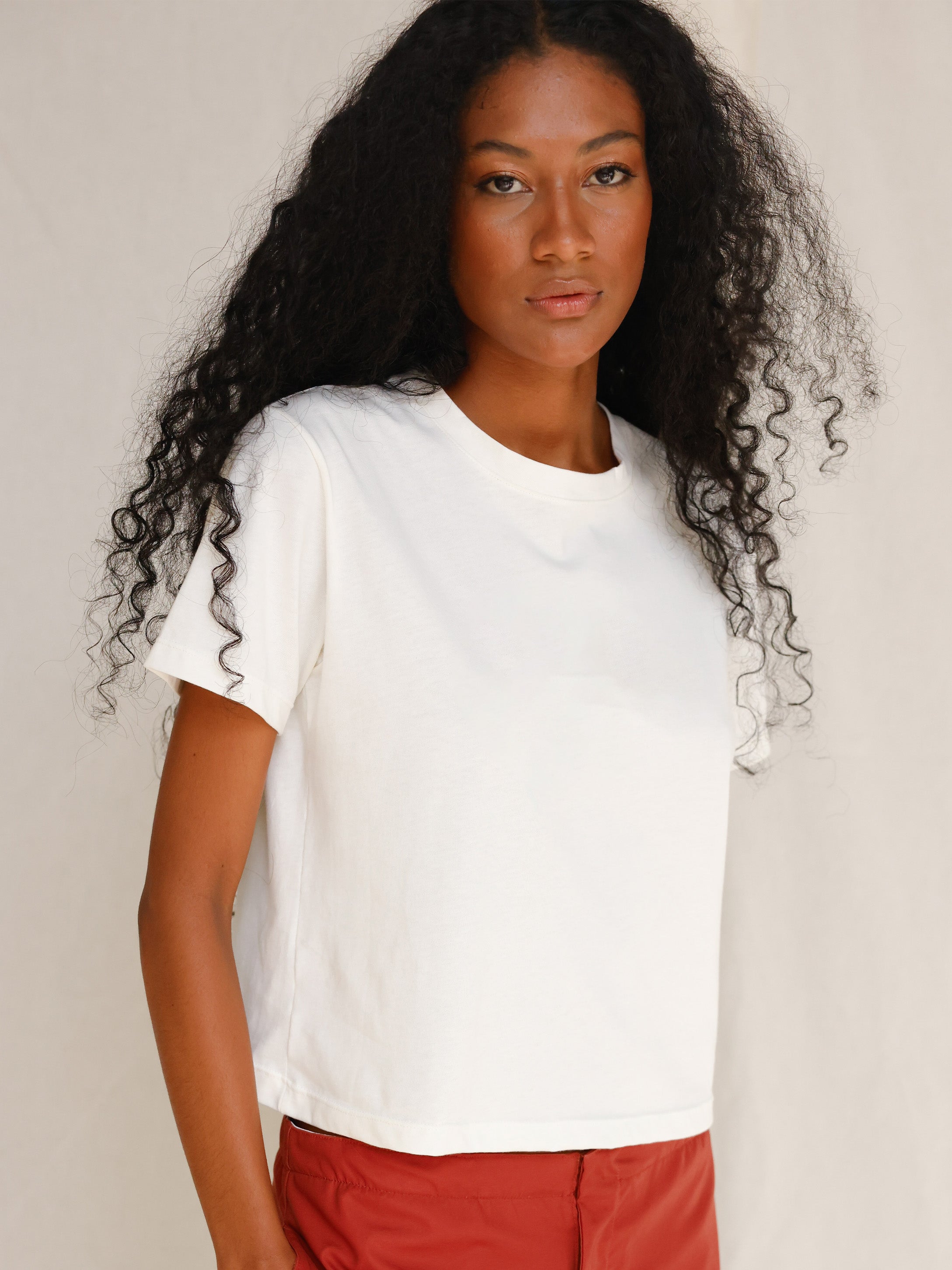 Front close-up view of model wearing plain off-white cotton t-shirt 